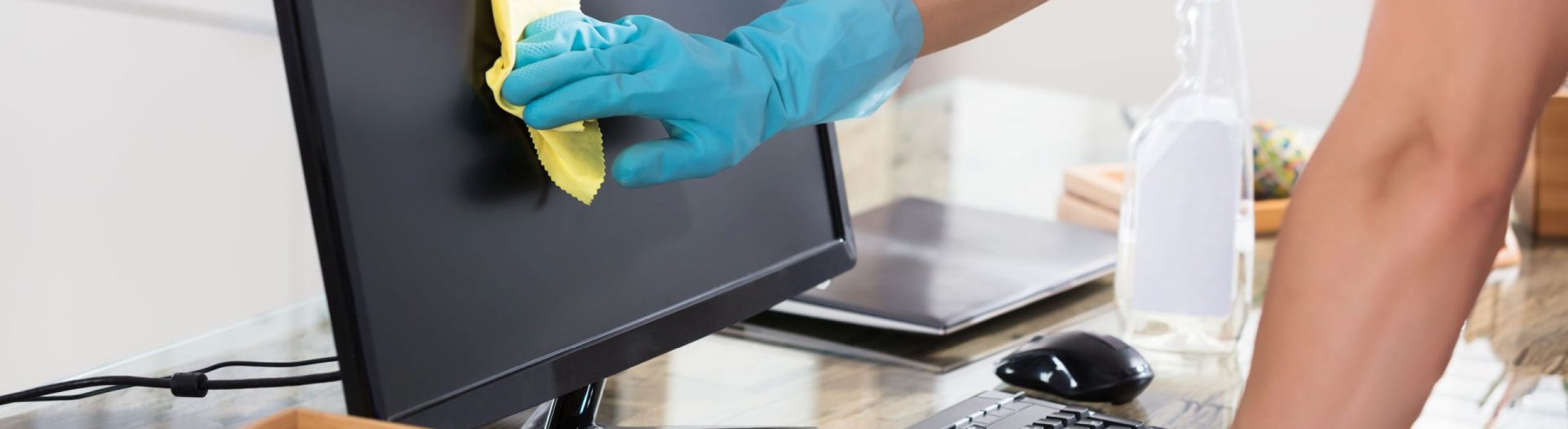 Close-up Of A Janitor's Hand Wearing Gloves Cleaning Computer Screen With Rag