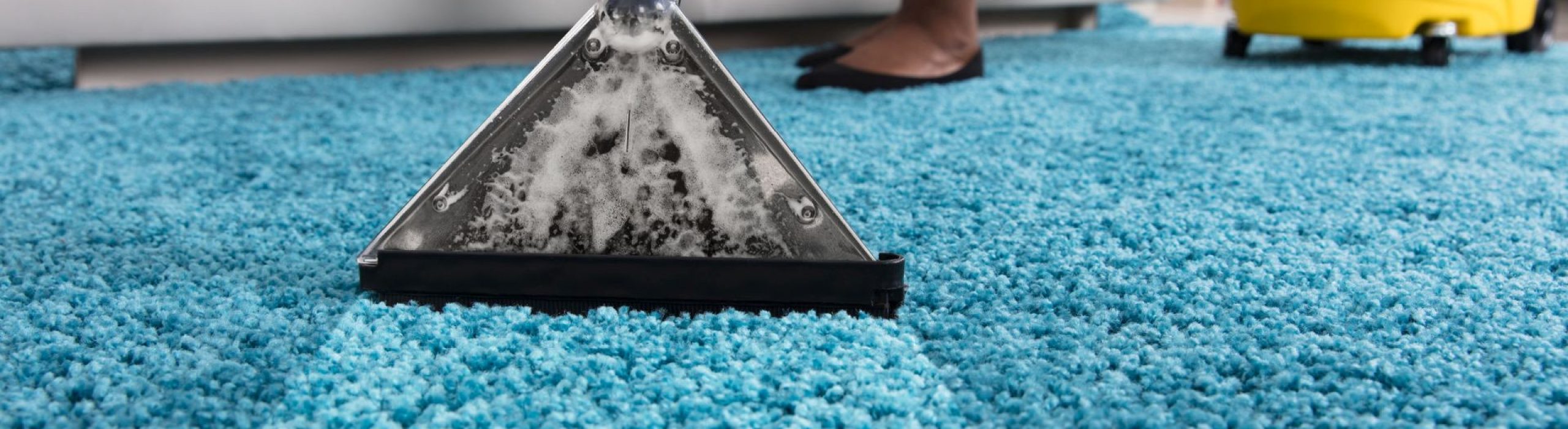 Person Using Vacuum Cleaner For Cleaning Blue Carpet At Home